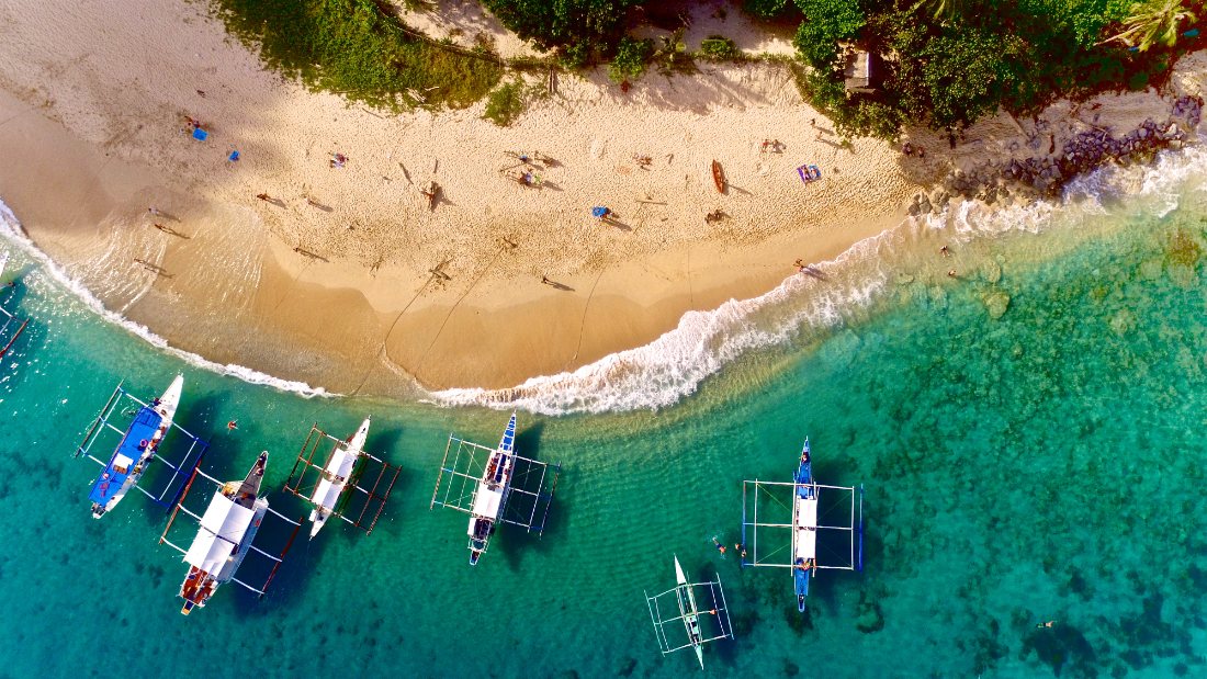 Island-hopping boats on a white-sand beach in the Philippines